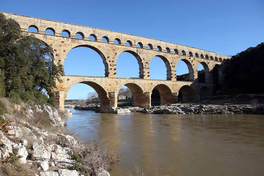 Which empire built vast roads and aqueducts to improve trade and communication?